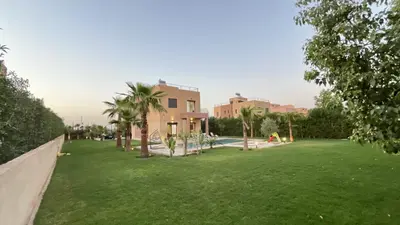 a large yard with a building and palm trees at Villa house 24 in Najem