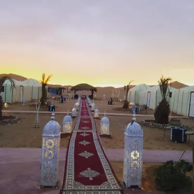 a row of tents with lights in the desert at moon luxury Dessert camp in Merzouga