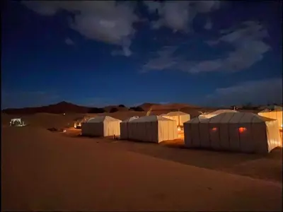 a group of tents in the desert at night at moon luxury Dessert camp in Merzouga