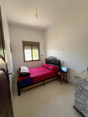 a small bedroom with a red bed with a window at Residence Nassim El Bahre in Oulad Akkou