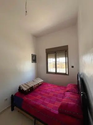 a red bed in a room with a window at Residence Nassim El Bahre in Oulad Akkou
