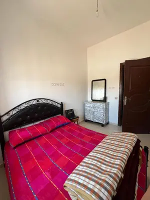 a bedroom with a large bed with a red blanket at Residence Nassim El Bahre in Oulad Akkou