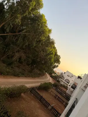 a tree and a fence next to a house at Le séjour idéal in Oulad Akkou