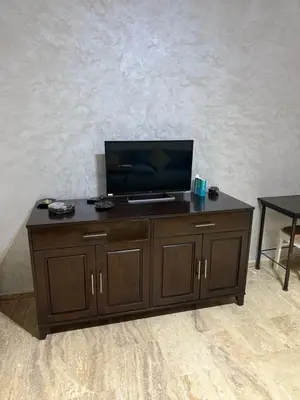 a wooden entertainment center with a flat screen tv on top at Le séjour idéal in Oulad Akkou