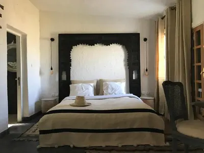 a bedroom with a large bed with a hat on it at Le Gîte Dayet Aoua