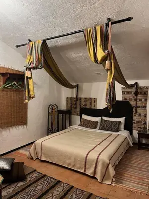 a bedroom with a bed with curtains hanging from the ceiling at Le Gîte Dayet Aoua