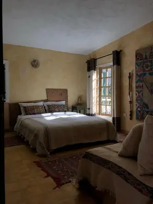 a bedroom with a large bed and a window at Le Gîte Dayet Aoua