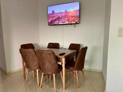a dining room table with chairs and a television on the wall at Diamond Fes Apartment in Fès