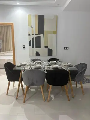 a dining room with a table with chairs and a painting at New Design in Today's Style in Oulad Akkou
