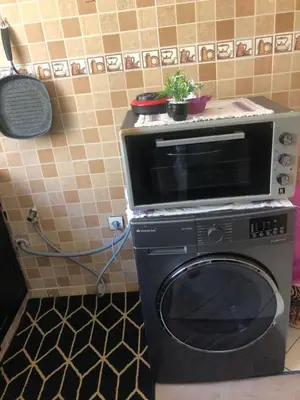 a microwave sitting on top of a washer in a kitchen at Résidence Nassim al bahr6 in Oulad Akkou