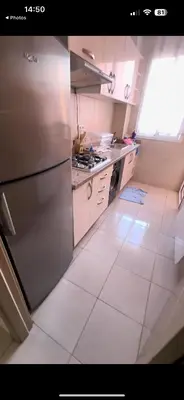 a kitchen with white tile floors and a stainless steel refrigerator at Samira in Oulad Akkou