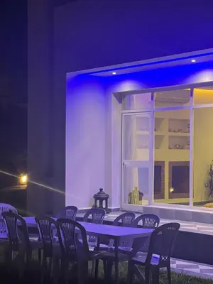 a table with chairs in front of a building at night at Villa Belle Rive Estate in Oulad Akkou