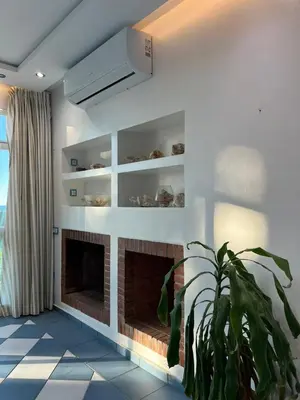 a living room with a fireplace and a plant at Villa Belle Rive Estate in Oulad Akkou