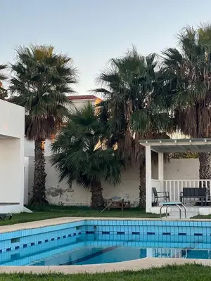 a swimming pool in front of a house with palm trees at Villa Belle Rive Estate in Oulad Akkou