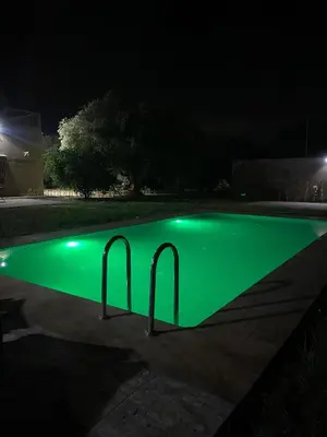 a swimming pool with green illumination at night at villa cherif in Azib Oulad Lâdem