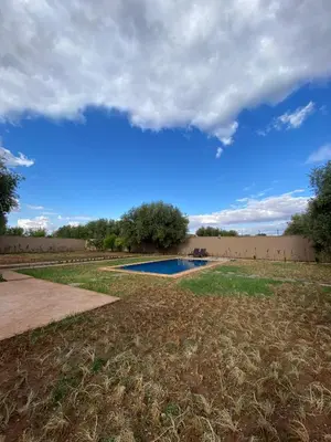a swimming pool in the middle of a field at villa cherif in Azib Oulad Lâdem