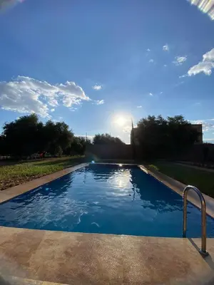 a swimming pool with the sun in the background at villa cherif in Azib Oulad Lâdem