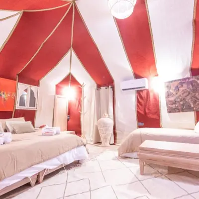 a bedroom with two beds and a red ceiling at Luxury camps merzouga in Merzouga