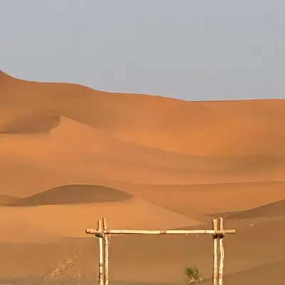 a wooden cross in the desert with mountains in the background at Luxury camps merzouga in Merzouga