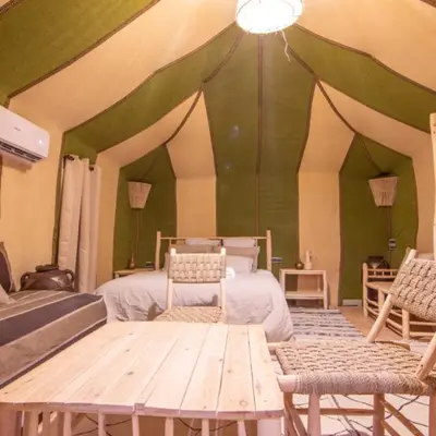 a room with a bed and two chairs and a table at Luxury camps merzouga in Merzouga