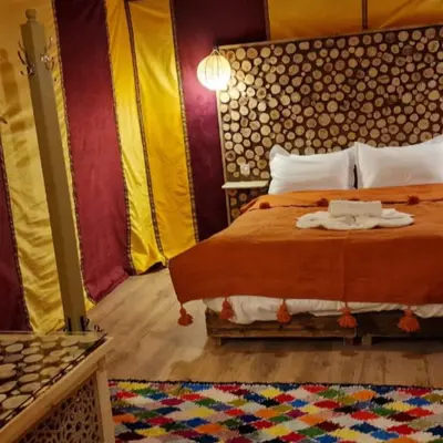 a bedroom with a bed and a rug at Luxury camps merzouga in Merzouga