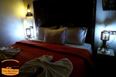 a bedroom with a bed with red sheets and pillows at Luxury camps merzouga in Merzouga