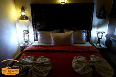 a bedroom with a large bed with red sheets and white pillows at Luxury camps merzouga in Merzouga