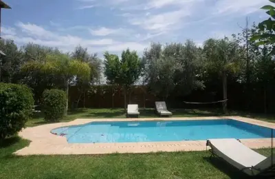 a swimming pool in a yard with two lounge chairs at Villa Flower in Oulad Akkou