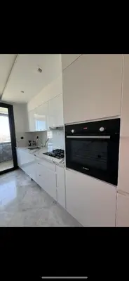 a kitchen with white cabinets and a black appliance at New luxury appartement in Oulad Akkou