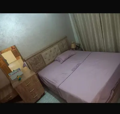 a bedroom with a purple bed and a night stand at اصيلة in Oulad Akkou