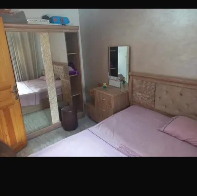 a small bedroom with a bed and a mirror at اصيلة in Oulad Akkou