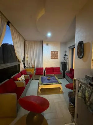 a living room with red couches and a table at Sidi rahal Blanca beach in Zaouia Sidi Rahkal