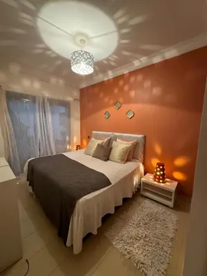 a bedroom with a large bed with orange walls at Sidi rahal Blanca beach in Zaouia Sidi Rahkal