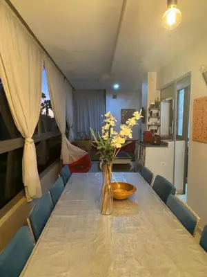 a dining room table with a vase of flowers on it at Sidi rahal Blanca beach in Zaouia Sidi Rahkal