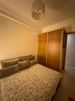 a bedroom with a bed and a wooden cabinet at Sidi rahal Blanca beach in Zaouia Sidi Rahkal