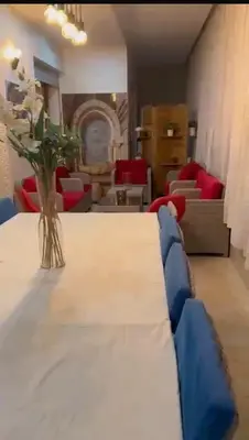 a dining room with a table and a vase of flowers at Sidi rahal Blanca beach in Zaouia Sidi Rahkal