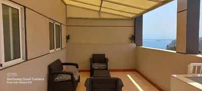 a balcony with chairs and a view of the ocean at Appartement vue mer quartier port 4 in Oulad Akkou