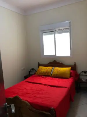 a bedroom with a red bed with a window at مارتيل in Oulad Akkou