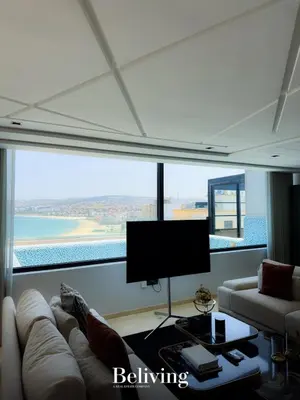 a living room with a couch and a flat screen tv at Luxurious penthouse with sea view in Oulad Akkou