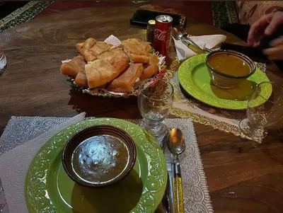 a table with green plates and a bowl of food at Gite le Calme café Restaurant Pizzeria in Bou Tharar