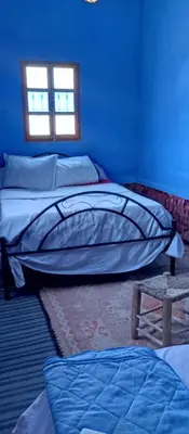 a room with two beds and a blue wall at Gite le Calme café Restaurant Pizzeria in Bou Tharar