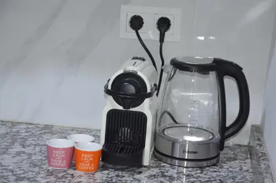 a black and white blender sitting on a counter with cups at Cozy Apartment close to amenities in Fès