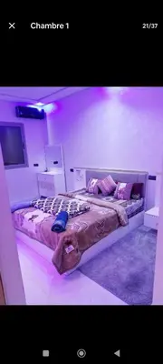 two beds in a room with purple lights at تجزئة الباهية in Meknès