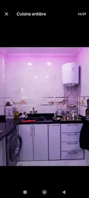 a kitchen with white cabinets and a sink and a appliance at تجزئة الباهية in Meknès