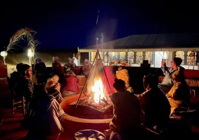 a group of people sitting around a fire at Merzouga Hosting & Camelride in Merzouga