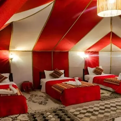 a room with three beds and a red ceiling at Merzouga Hosting & Camelride in Merzouga