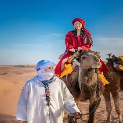 a woman is riding a camel in the desert at Merzouga Hosting & Camelride in Merzouga