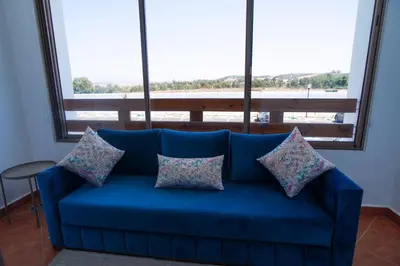 a blue couch in a room with a large window at La perle bleue de Beralmar Asilah in Oulad Akkou