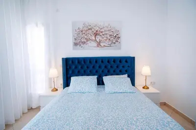 a blue bed in a white bedroom with two lamps at La perle bleue de Beralmar Asilah in Oulad Akkou
