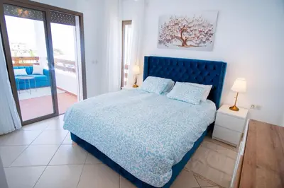 a bedroom with a blue bed and a balcony at La perle bleue de Beralmar Asilah in Oulad Akkou